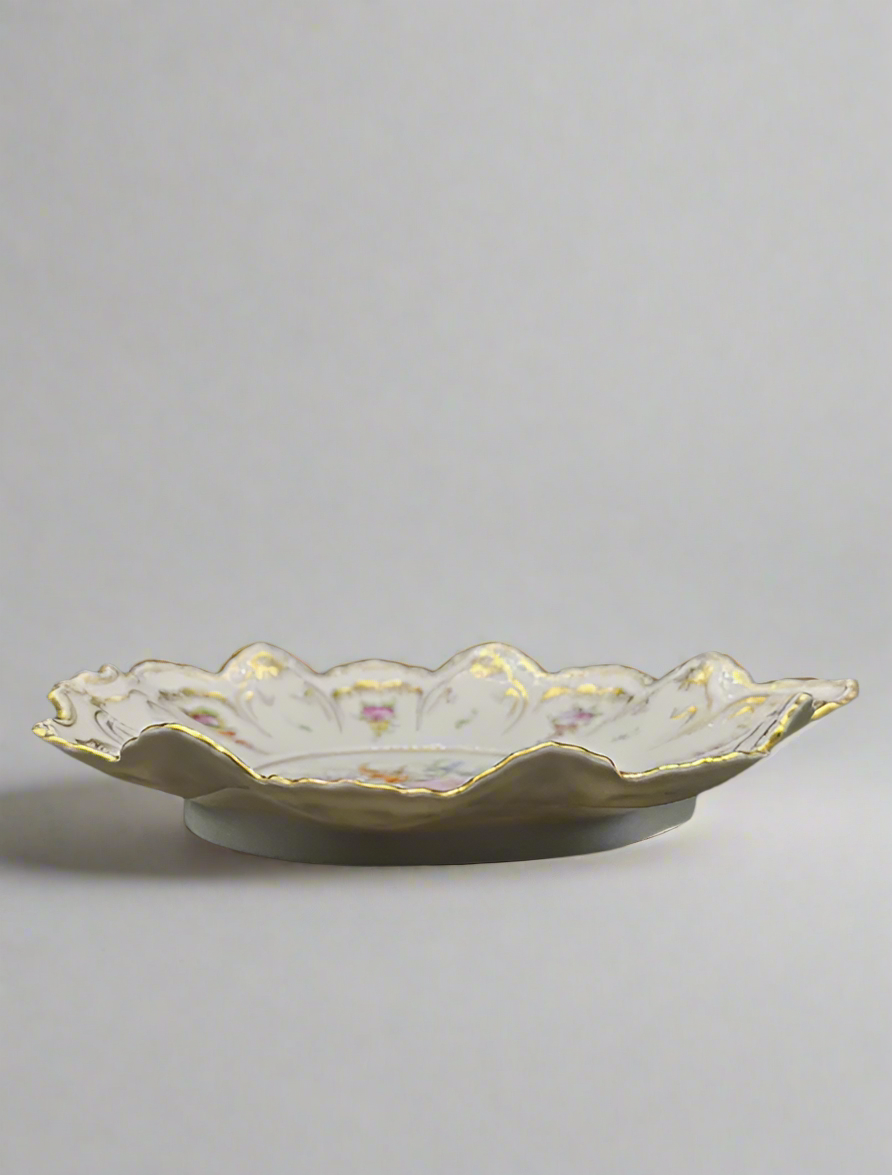 Decorative ceramic plate with scalloped edge on a gray background